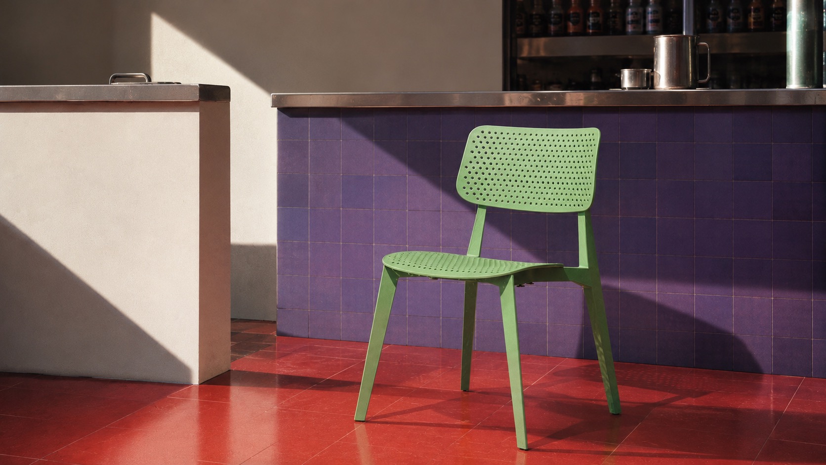 Green perforated café chair at a purple tiled counter in a sunlit interior